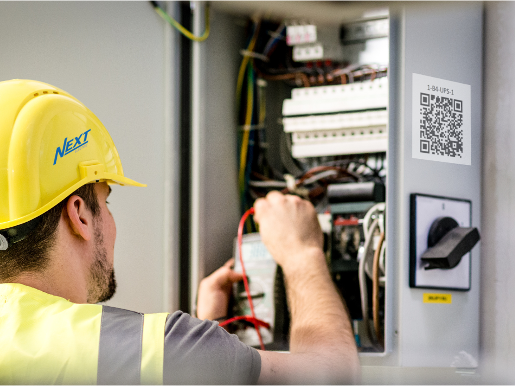 An electrician servicing an electric panel that has a QR code on its side