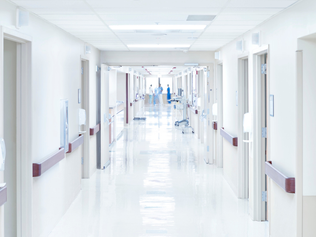 An image of a hospital hallway with doctors and nurses at the end.