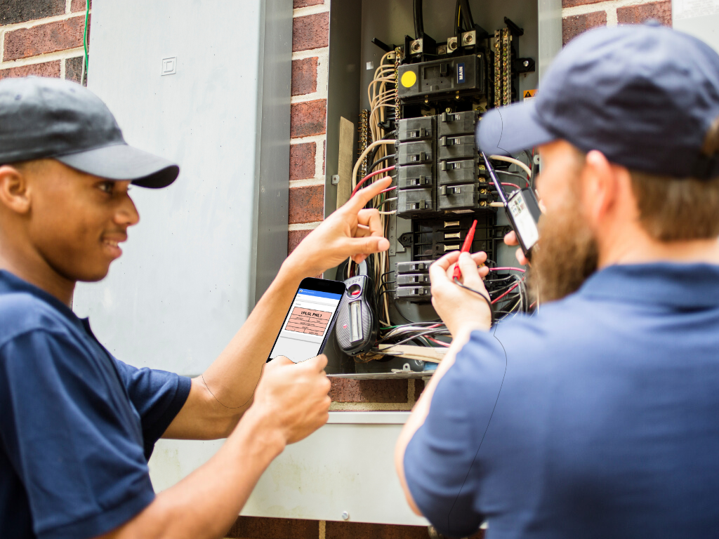 Two electricians working on an electrical panel